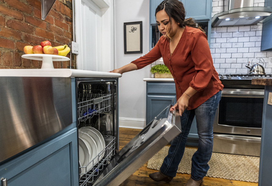 Woman closing a dishwasher in the kitchen