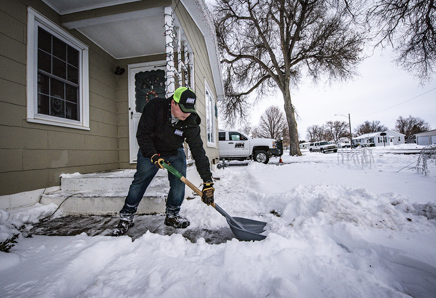 Man shoveling snow in front of a house