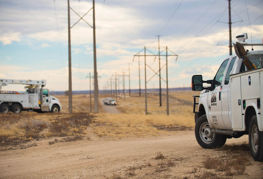 Utility trucks with electric poles in the background