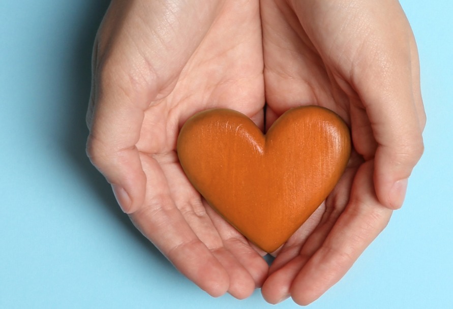 Hands holding a heart made of wood