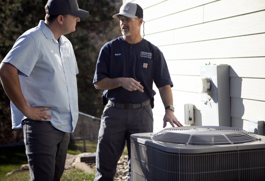 Service Guard technician talking to customer next to an AC unit outside a house
